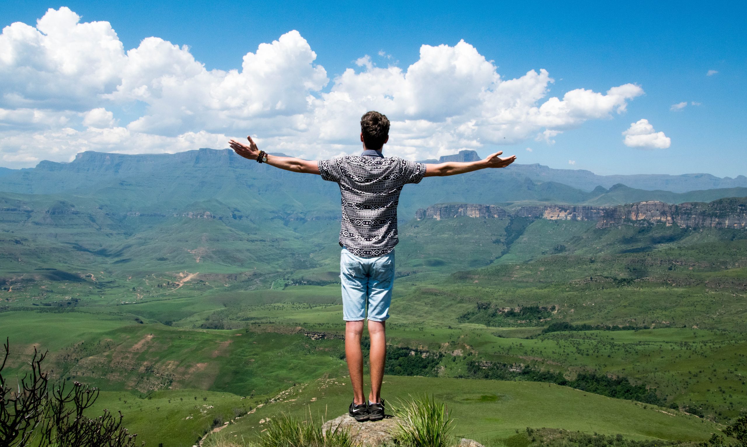Man with wide open arms on top of a mountain